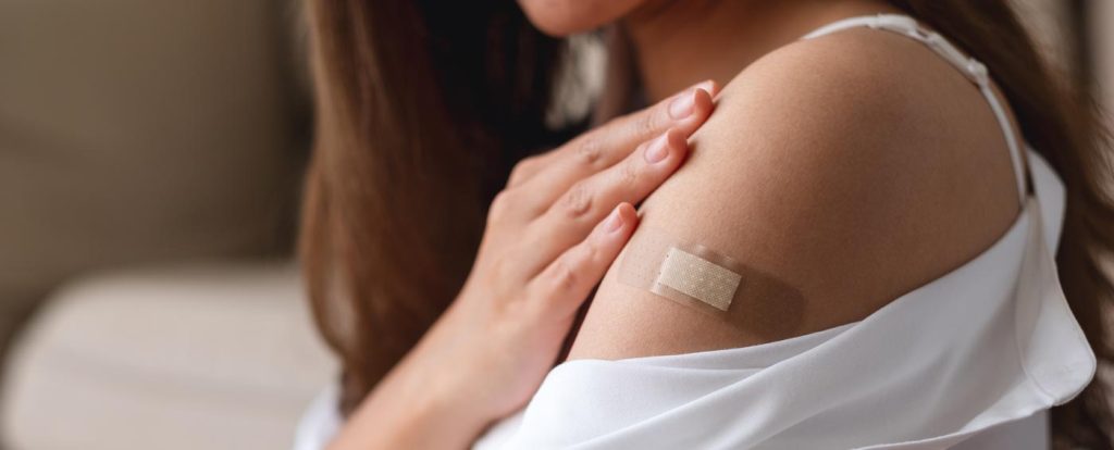 aes_image_impfungen_2023 Seitenansicht einer Frau mit einem Pflaster am Arm